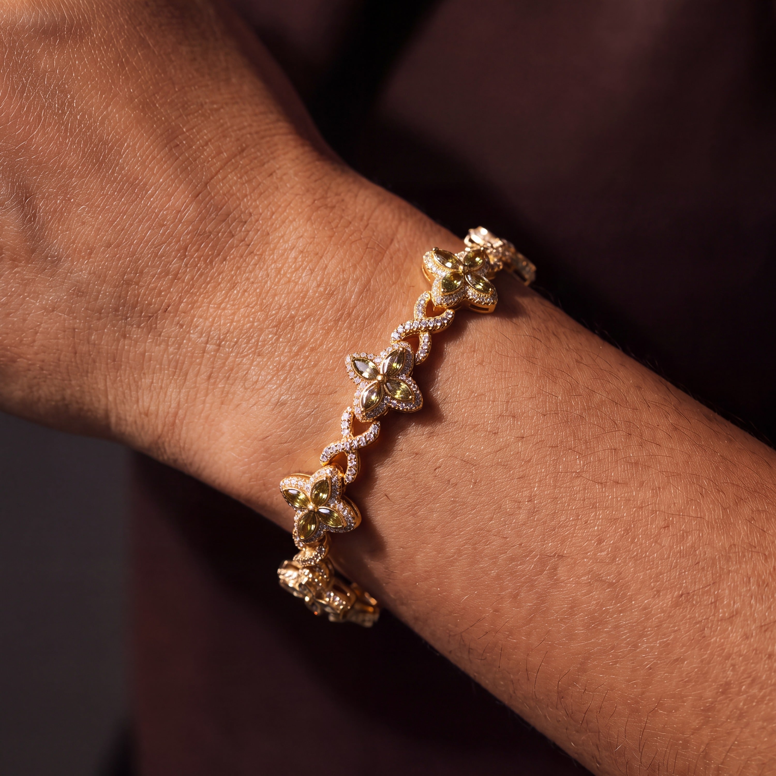 Gold-tone clover flower bracelet with olive-green marquise petals, worn on a wrist